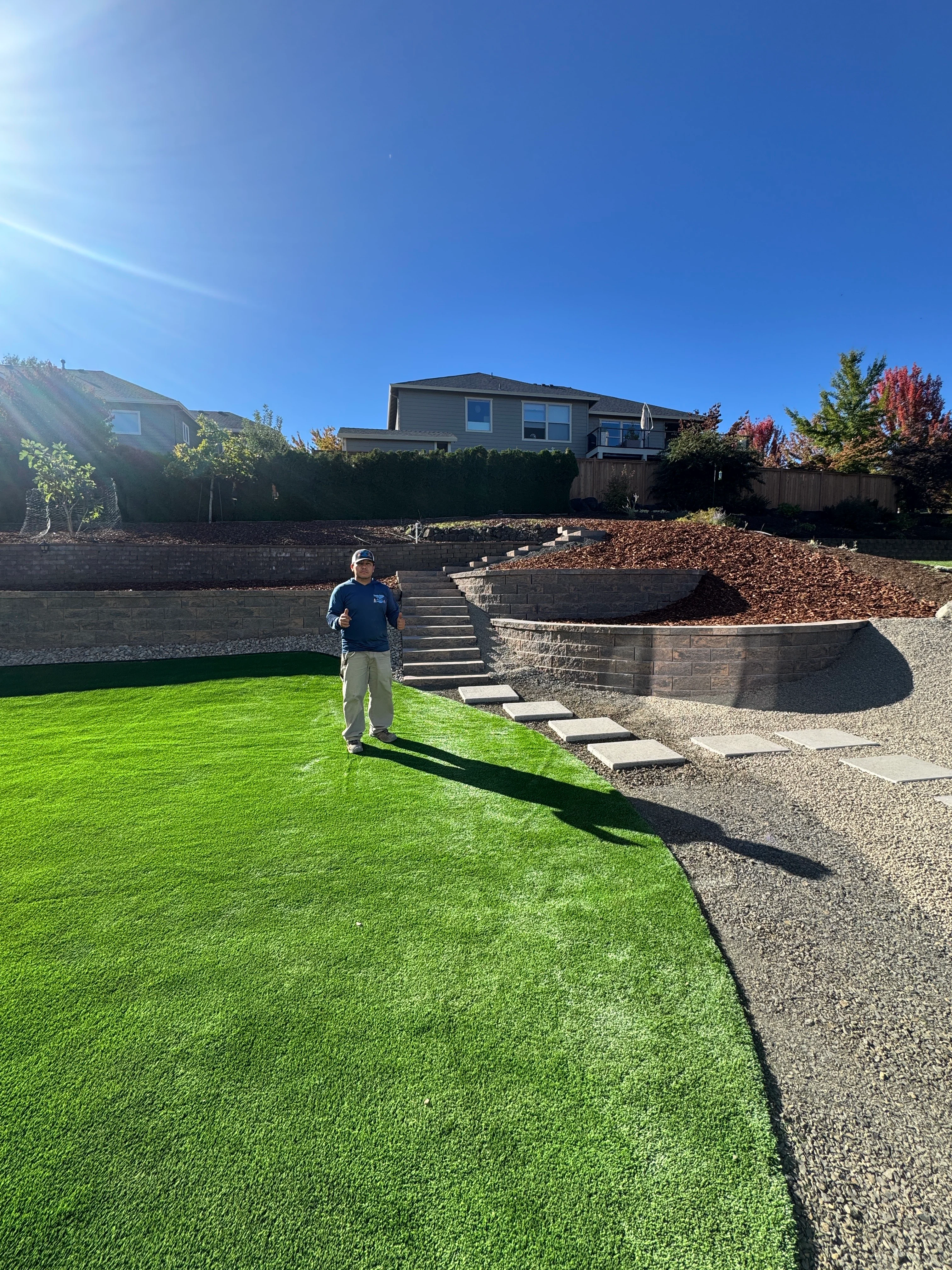 Outdoor hardscape project showing completed paver patio and landscaping work with professional tools and materials staged nearby.