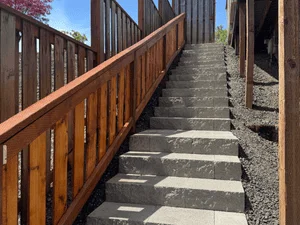 Concrete stepping stone walkway with wood vertical slat railing along narrow passage