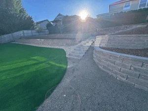 Stacked stone retaining wall with artificial turf and gravel pathway