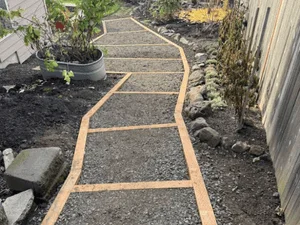 Curved paver pathway with timber borders and dark gray pavers in running bond pattern