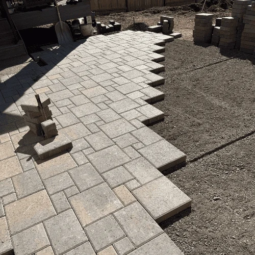 Gray concrete pavers in running bond pattern with gravel border and proper drainage slope