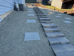Multi-level paver patio with concrete steps and gravel base during installation