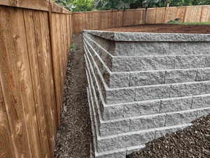 Concrete block retaining wall with metal reinforcement and landscape fabric drainage system