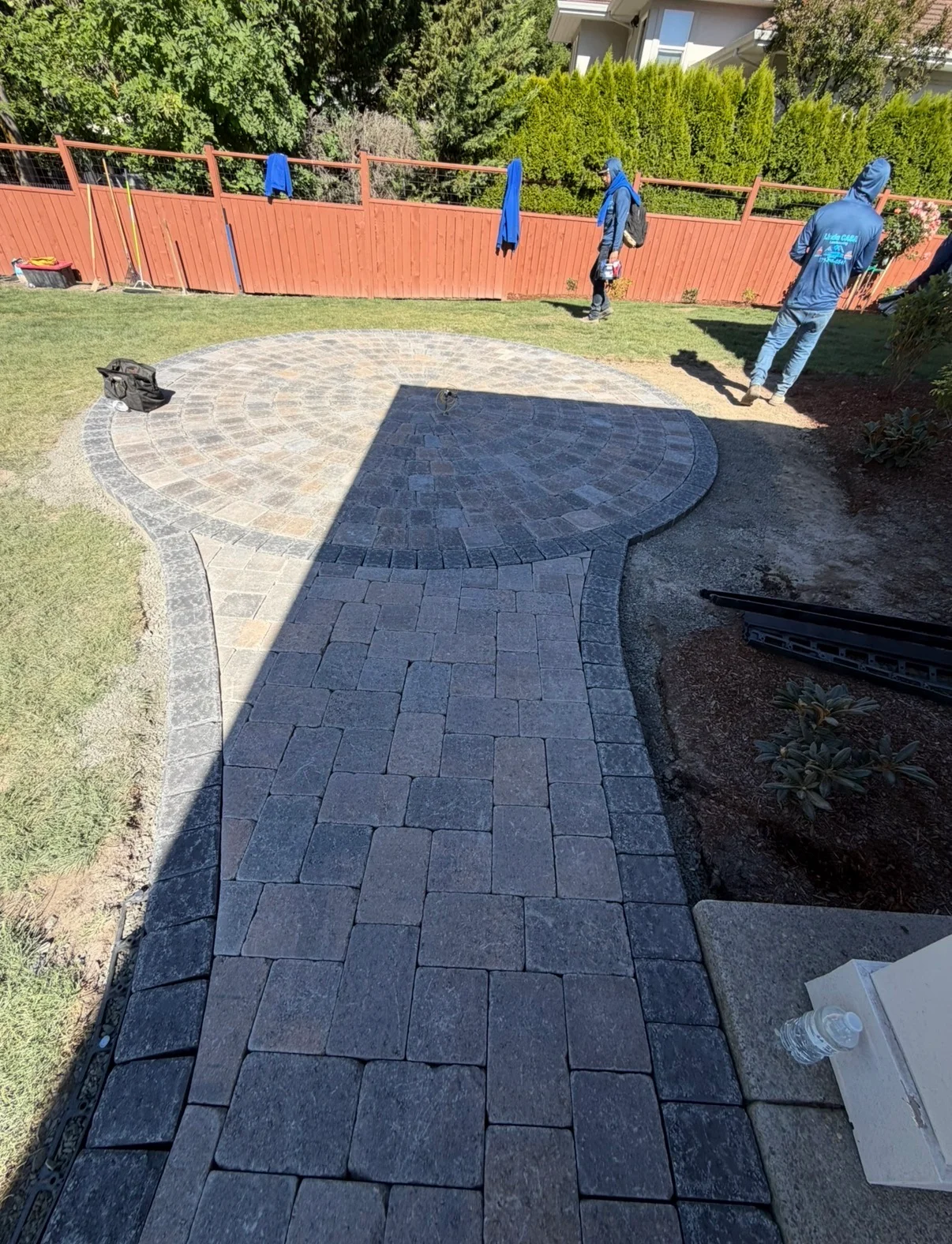 Dark charcoal pavers installed in curved running bond pattern with decorative border