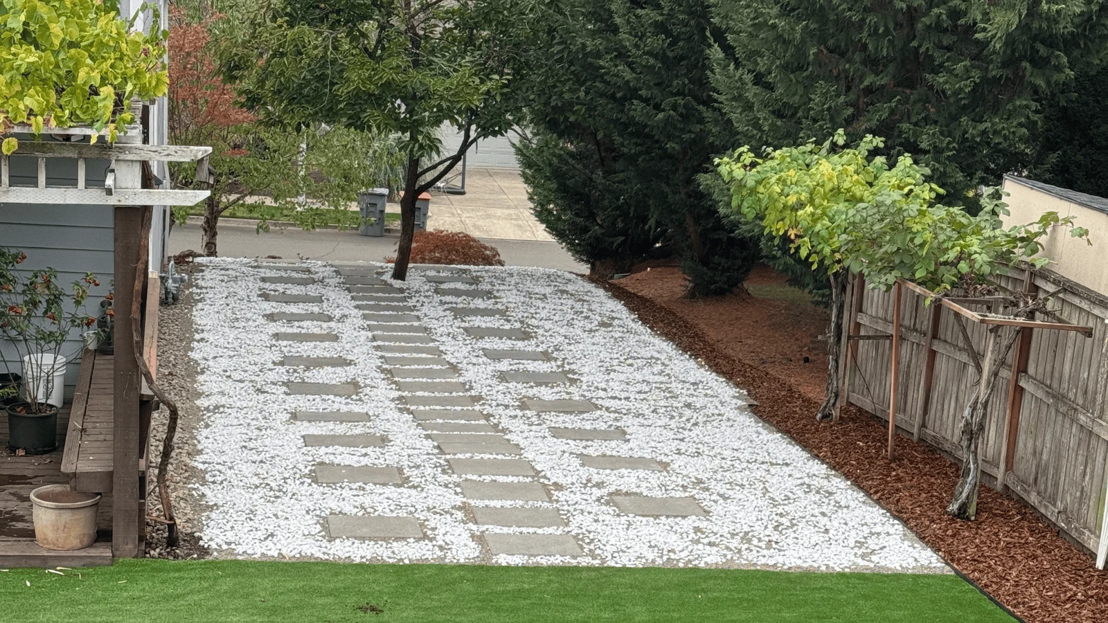 Rectangular concrete pavers with white river rock base in backyard landscape