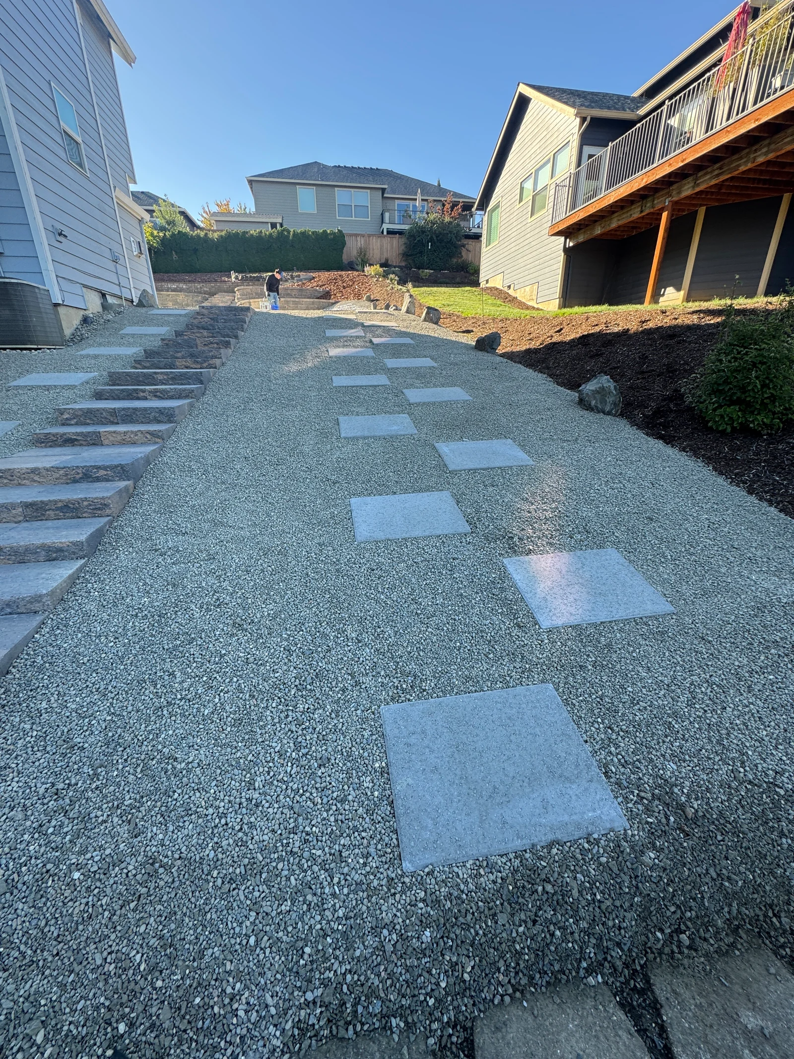 Concrete stepping stone pavers in gravel pathway between residential homes