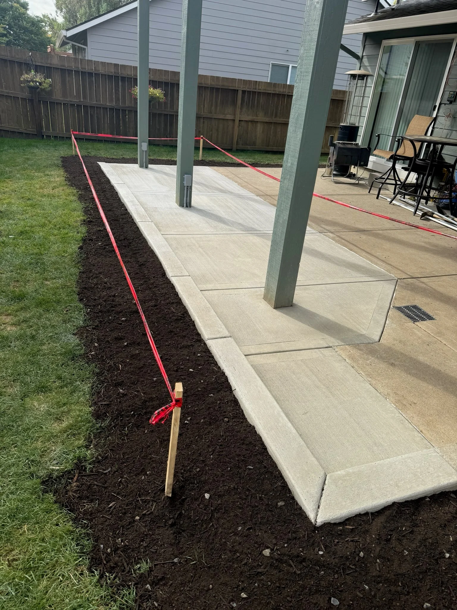 Concrete patio slabs with control joints under pergola with steel posts and drainage system