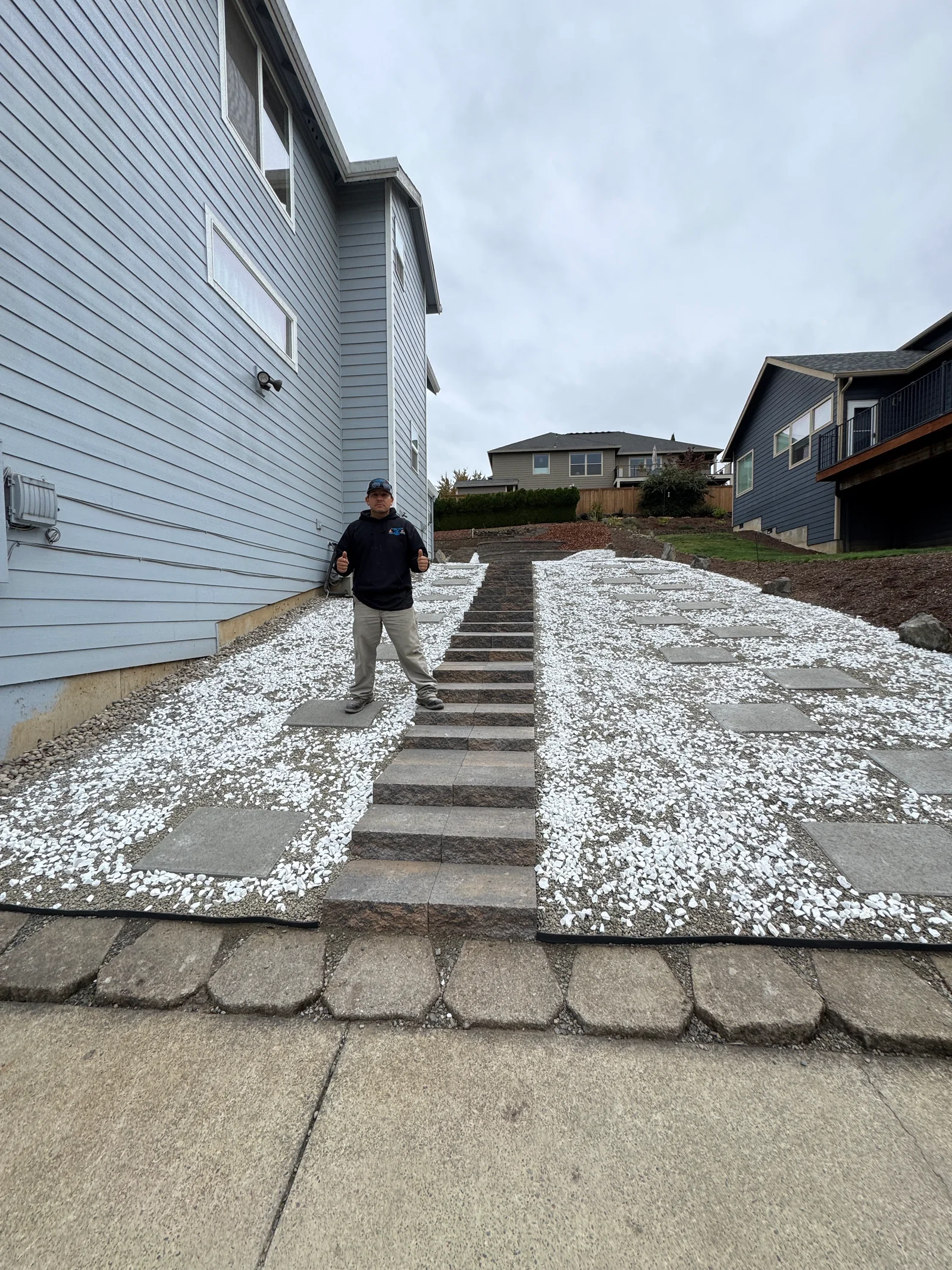 Concrete stepping stone paver pathway with white crushed gravel base between house and driveway