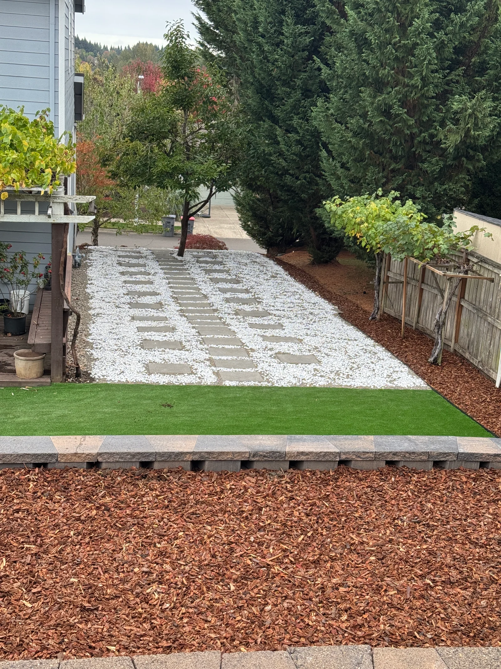Light paver stepping stones in white gravel with landscape edging and mature trees