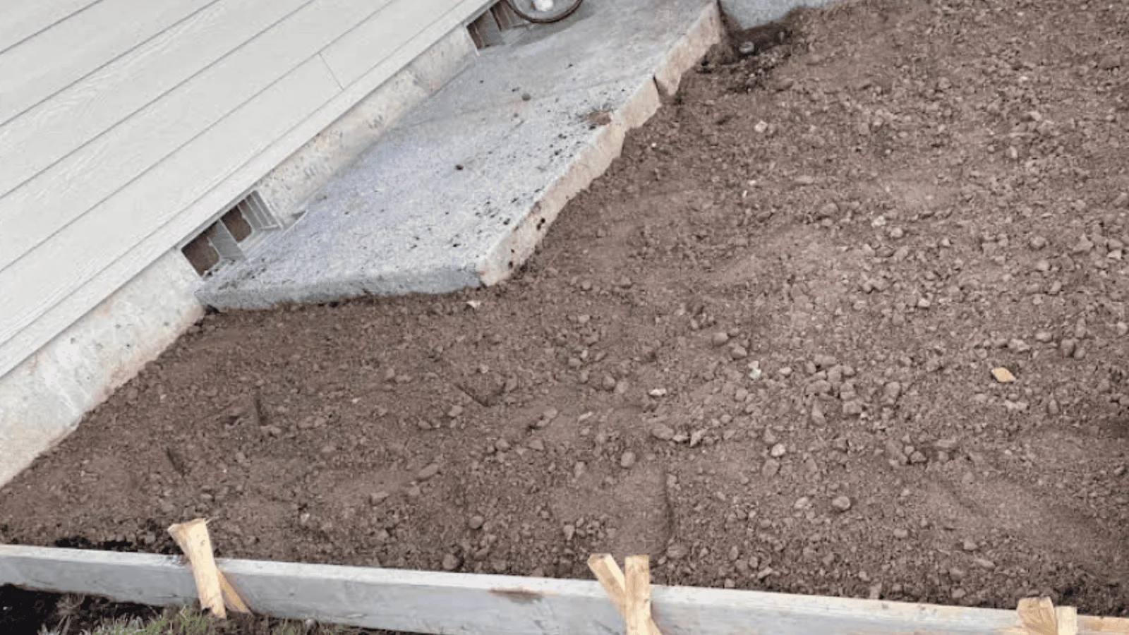 Concrete slab with gravel base and wooden forms for paver patio foundation